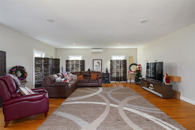 living room featuring an AC wall unit and light hardwood / wood-style flooring