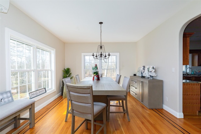 dining room with sink, light wood-type flooring, an inviting chandelier, and a wall unit AC