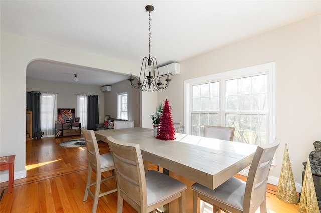 dining room featuring a chandelier, light hardwood / wood-style flooring, and a wall mounted AC