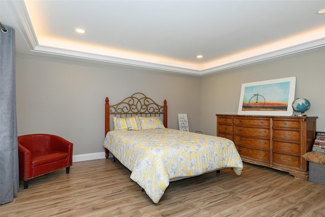 bedroom with a raised ceiling and light hardwood / wood-style flooring