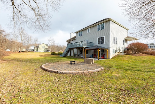 rear view of house featuring a lawn, a wooden deck, and a fire pit