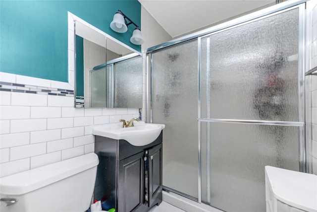 bathroom with vanity, toilet, tile walls, and walk in shower