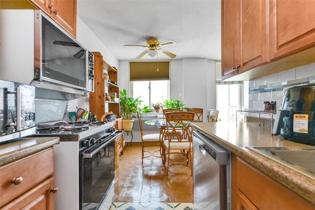 kitchen featuring dishwasher, ceiling fan, a wealth of natural light, and gas range oven