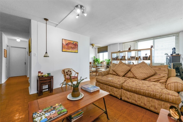 living room featuring ceiling fan and a textured ceiling