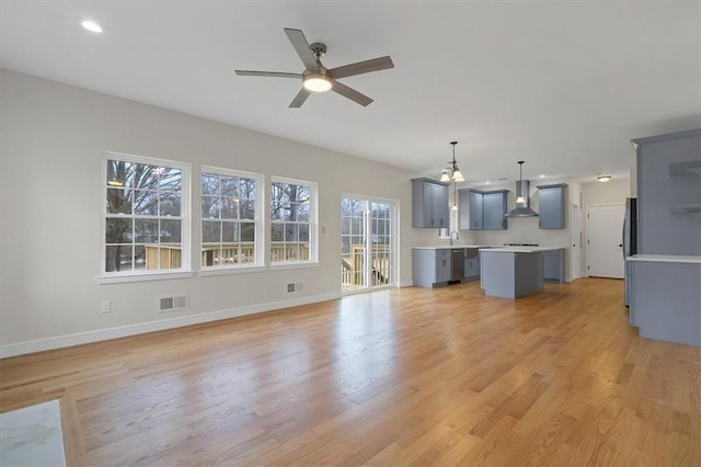 unfurnished living room with ceiling fan, light wood-type flooring, and sink