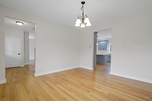 empty room featuring a chandelier and light hardwood / wood-style floors