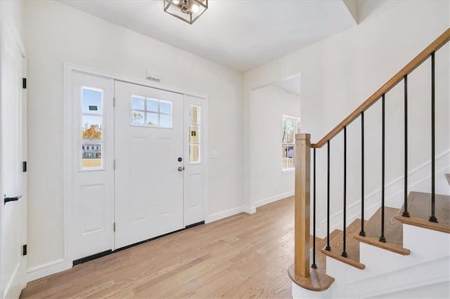 entrance foyer with stairway, light wood-style flooring, and baseboards