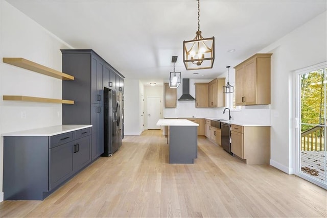 kitchen with a center island, wall chimney exhaust hood, light wood-style floors, and stainless steel appliances