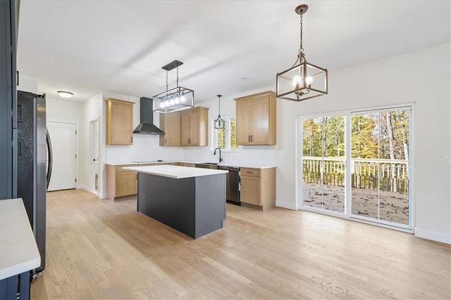 kitchen featuring stainless steel appliances, a barn door, wall chimney exhaust hood, light wood-type flooring, and a center island