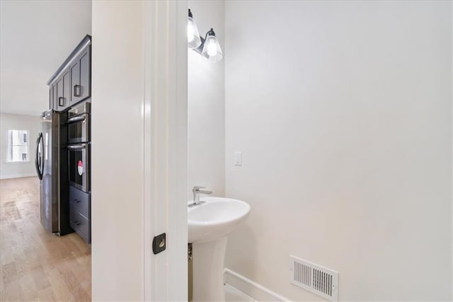 bathroom with visible vents, baseboards, and wood finished floors