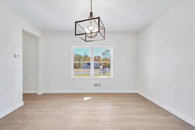 unfurnished dining area with light wood-style flooring, a notable chandelier, baseboards, and visible vents