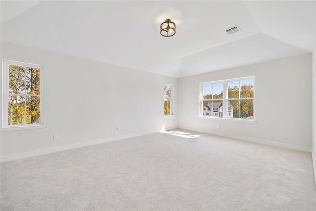 carpeted spare room featuring visible vents, baseboards, and vaulted ceiling