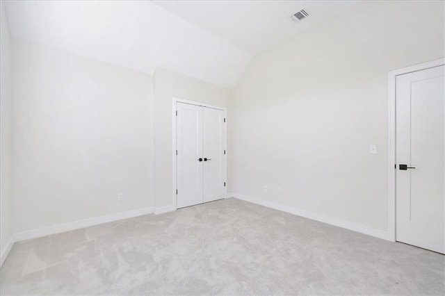 spare room with visible vents, light carpet, baseboards, and vaulted ceiling