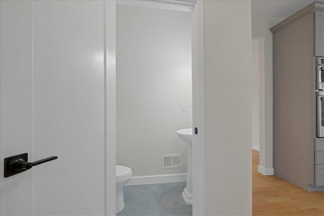 bathroom featuring hardwood / wood-style flooring and toilet