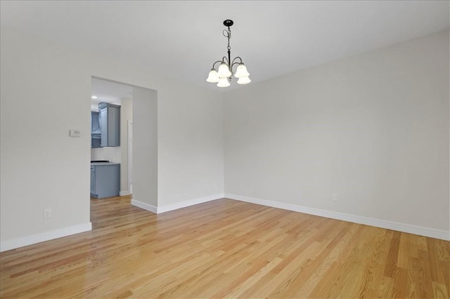 empty room featuring light hardwood / wood-style flooring and a notable chandelier