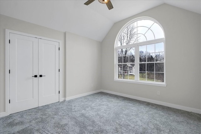 unfurnished bedroom featuring carpet, a closet, ceiling fan, and lofted ceiling