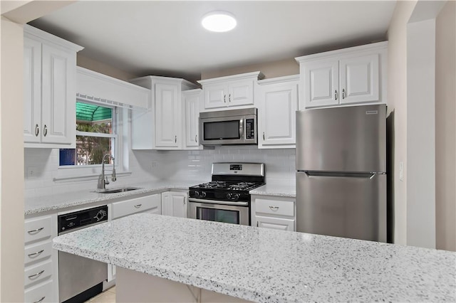 kitchen featuring decorative backsplash, light stone counters, stainless steel appliances, sink, and white cabinets