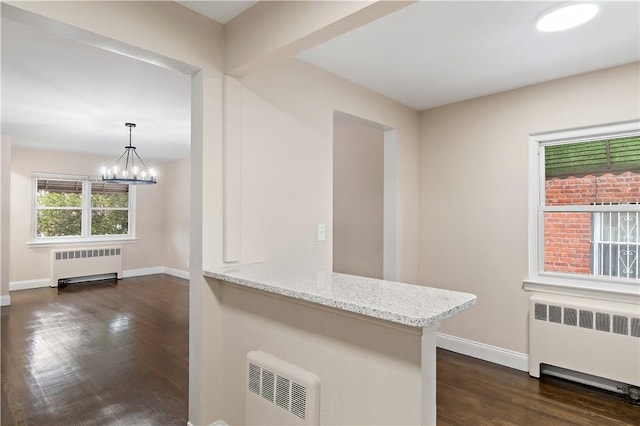 kitchen featuring radiator heating unit, light stone counters, hanging light fixtures, and a notable chandelier