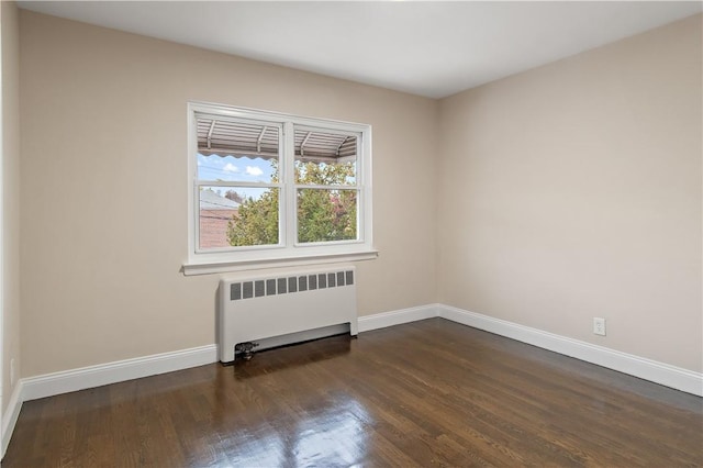 unfurnished room featuring radiator heating unit and dark wood-type flooring