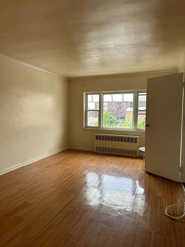 empty room featuring wood-type flooring and radiator