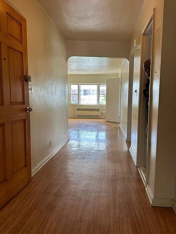 hallway featuring radiator heating unit and hardwood / wood-style floors