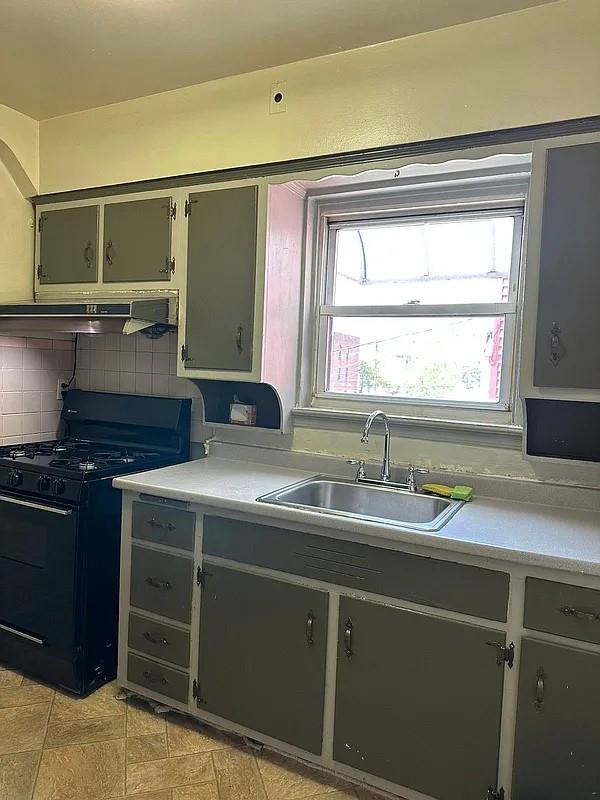 kitchen with black gas range, sink, and tasteful backsplash