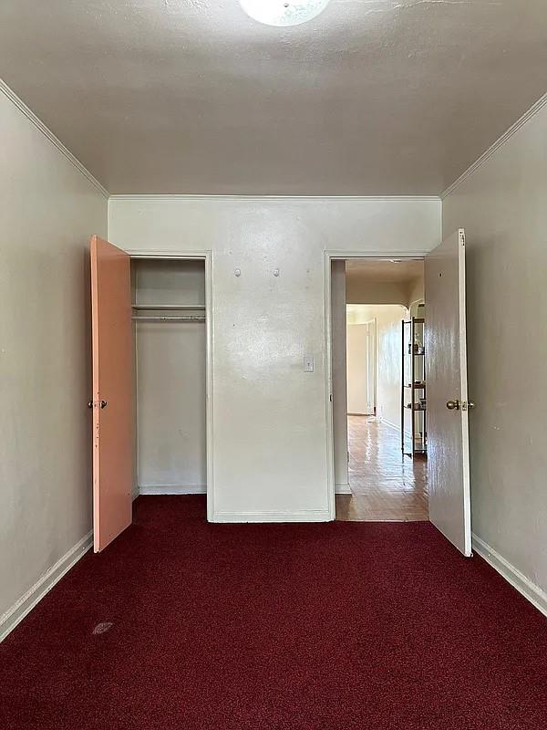 unfurnished bedroom with crown molding, a closet, and light carpet