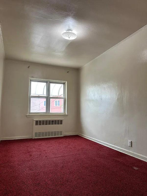 empty room featuring carpet flooring and radiator