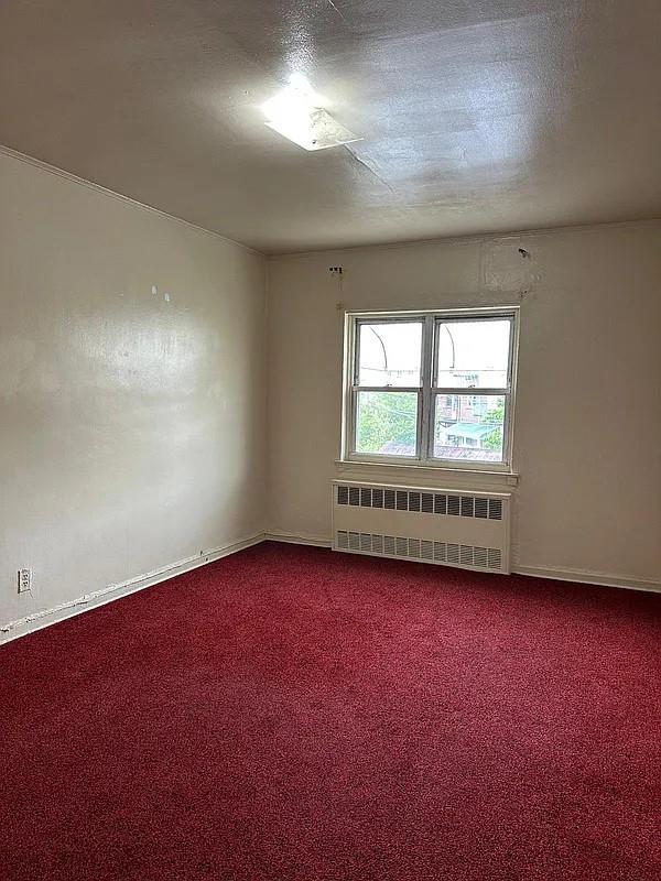 empty room with carpet flooring, radiator heating unit, and a textured ceiling