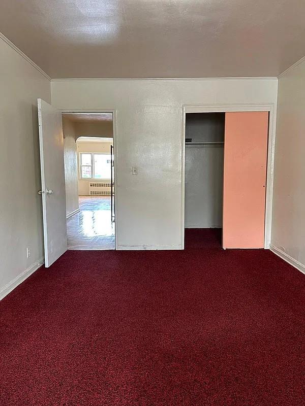 unfurnished bedroom featuring radiator heating unit, carpet floors, a closet, and a textured ceiling