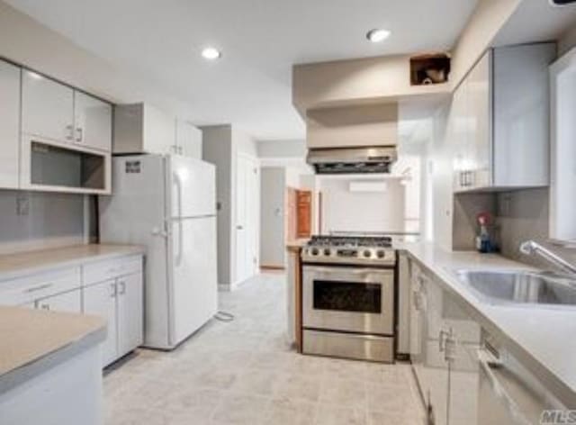 kitchen with ventilation hood, sink, white cabinets, and appliances with stainless steel finishes