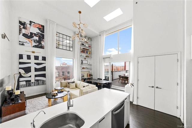 kitchen with dark wood-type flooring, hanging light fixtures, stainless steel dishwasher, a towering ceiling, and white cabinetry