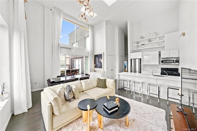 living room with dark hardwood / wood-style flooring, a towering ceiling, a wealth of natural light, and a skylight