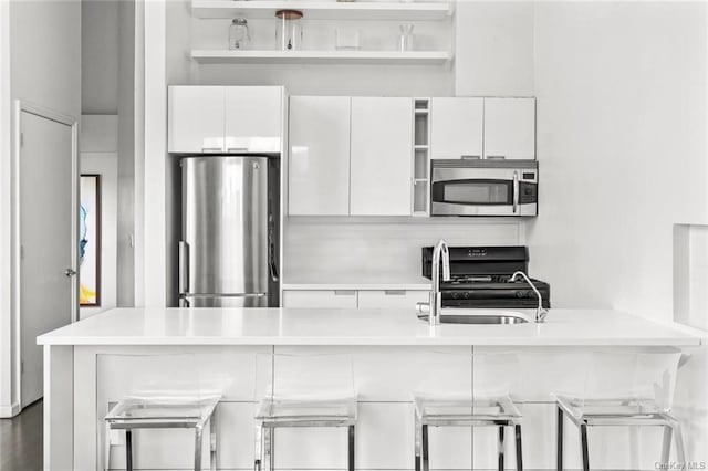 kitchen with white cabinets, a kitchen bar, stainless steel appliances, and sink