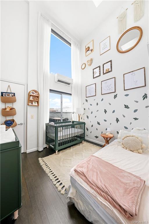 bedroom featuring an AC wall unit, dark wood-type flooring, and a towering ceiling