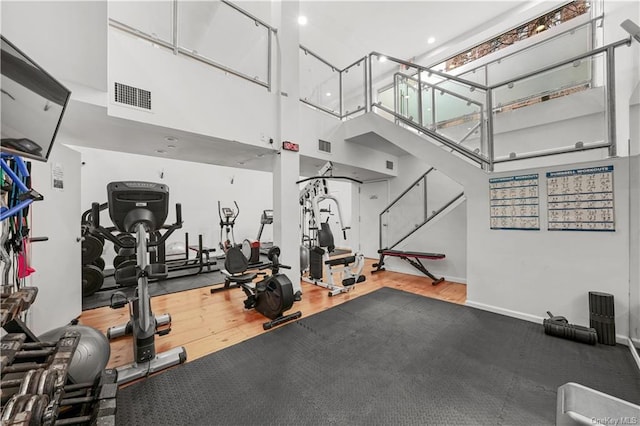 workout area with hardwood / wood-style floors and a towering ceiling