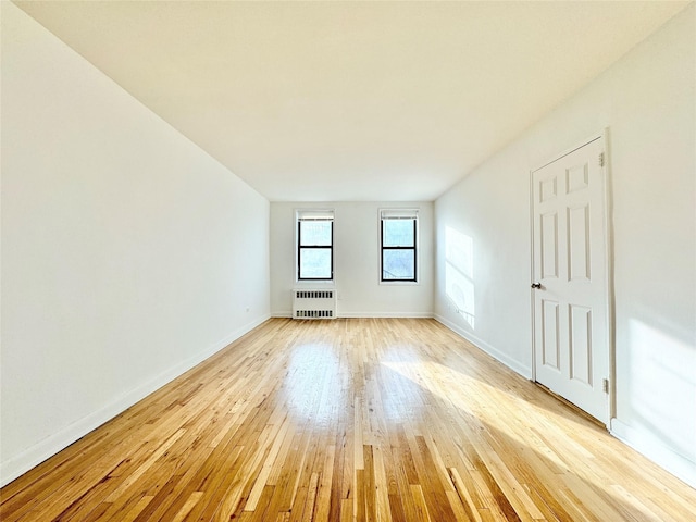 spare room featuring radiator heating unit and light hardwood / wood-style flooring