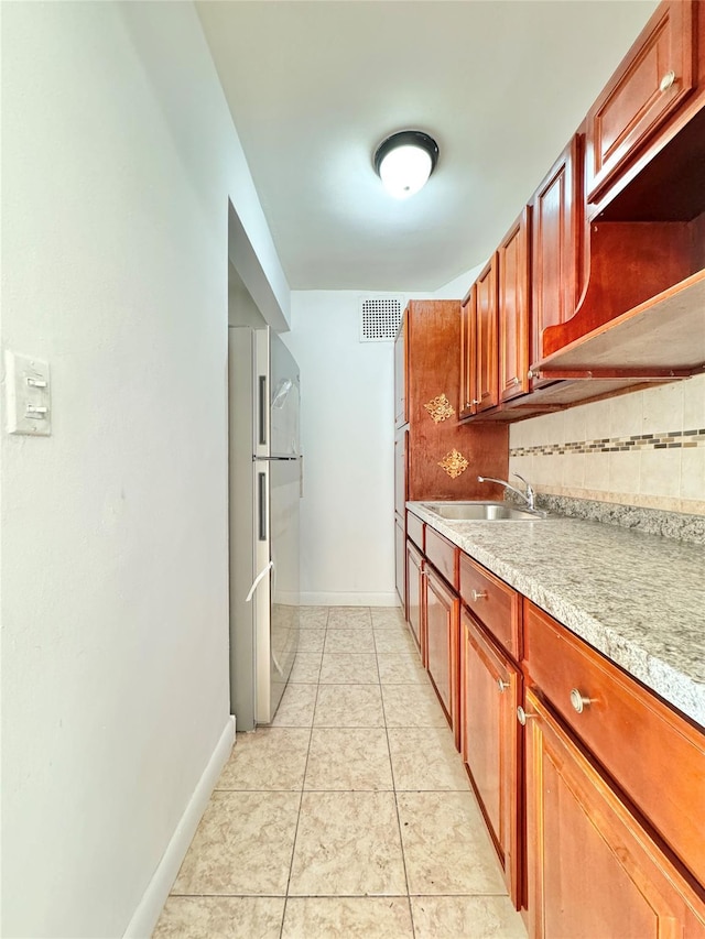 kitchen featuring high end fridge, light tile patterned floors, sink, and tasteful backsplash