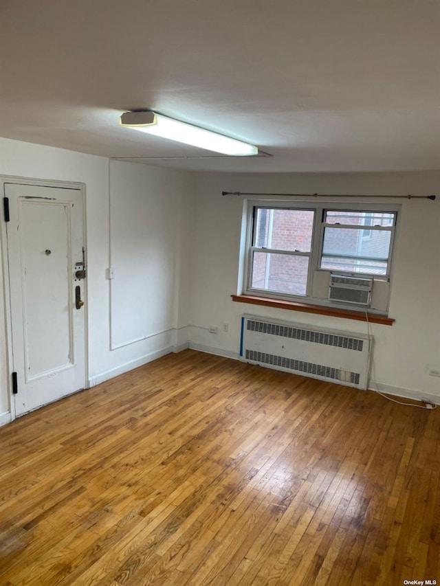 empty room featuring wood-type flooring, radiator, and cooling unit