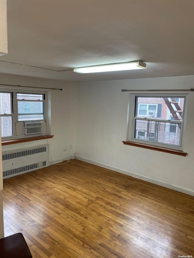 empty room featuring radiator, cooling unit, and wood-type flooring