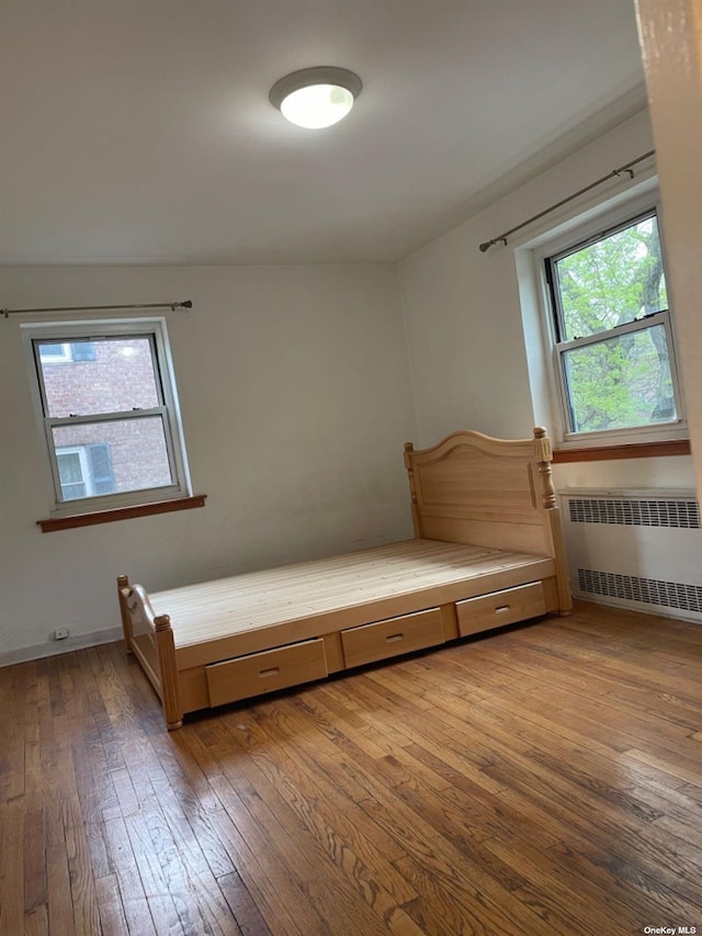 unfurnished bedroom featuring wood-type flooring and radiator heating unit