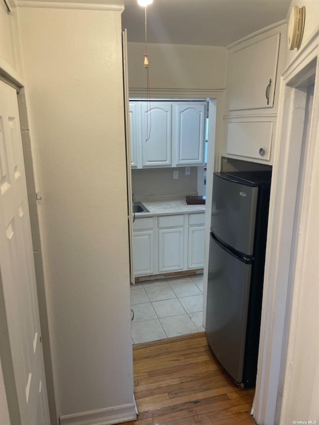 kitchen featuring light hardwood / wood-style floors, stainless steel fridge, white cabinetry, and sink