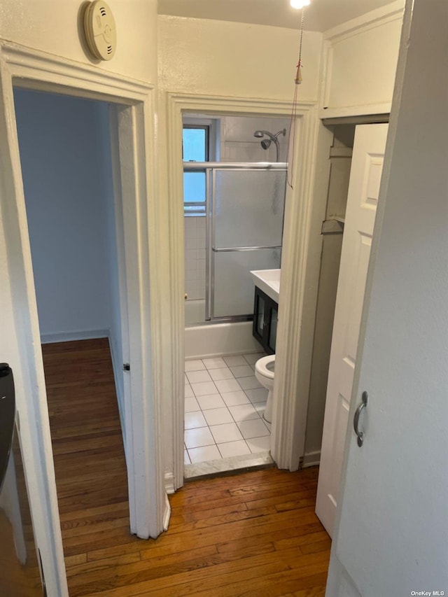 full bathroom with hardwood / wood-style floors, vanity, toilet, and enclosed tub / shower combo