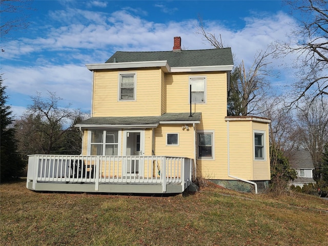 back of property featuring a deck and a yard