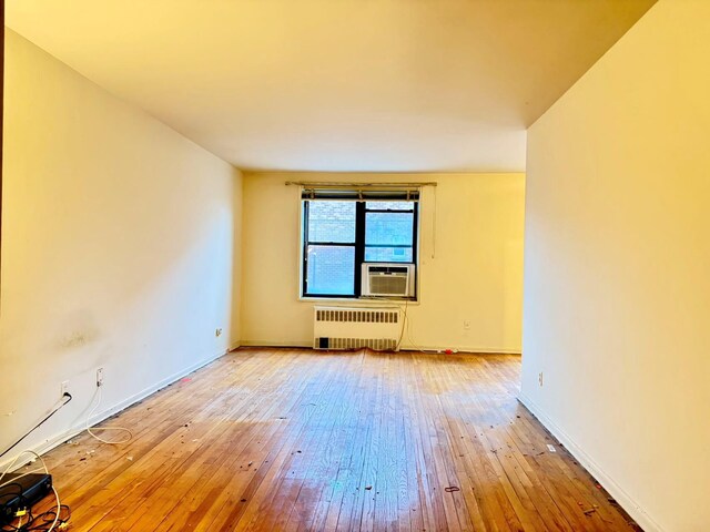 spare room with hardwood / wood-style flooring, radiator, and cooling unit