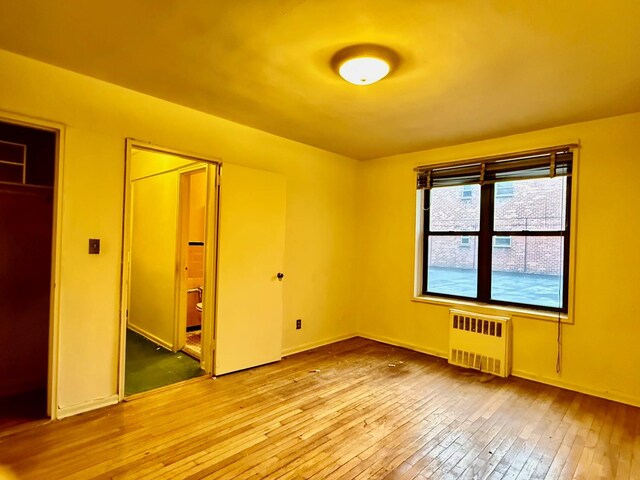 unfurnished bedroom featuring radiator, a closet, and light hardwood / wood-style floors