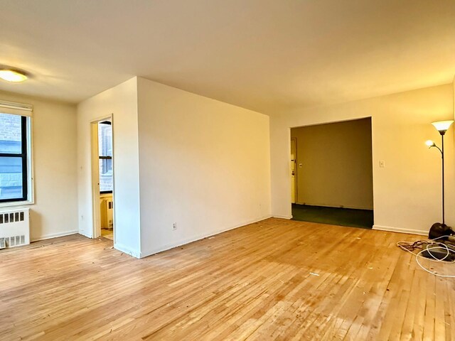 spare room featuring radiator and light wood-type flooring