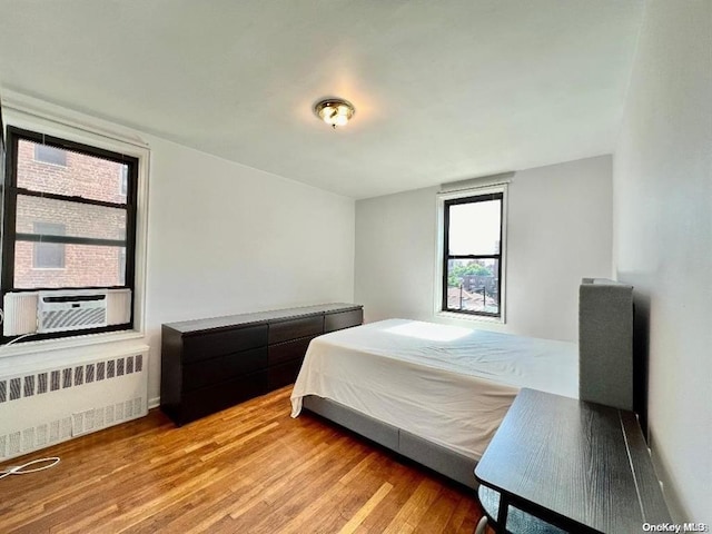 bedroom with hardwood / wood-style floors, cooling unit, and radiator