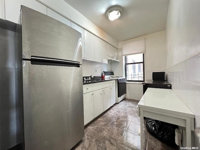 kitchen with stainless steel refrigerator, white cabinetry, white gas range, and sink