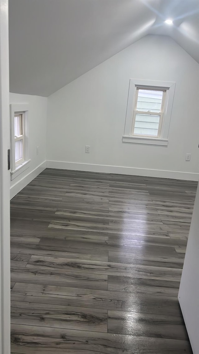 additional living space with dark hardwood / wood-style floors, vaulted ceiling, and a wealth of natural light